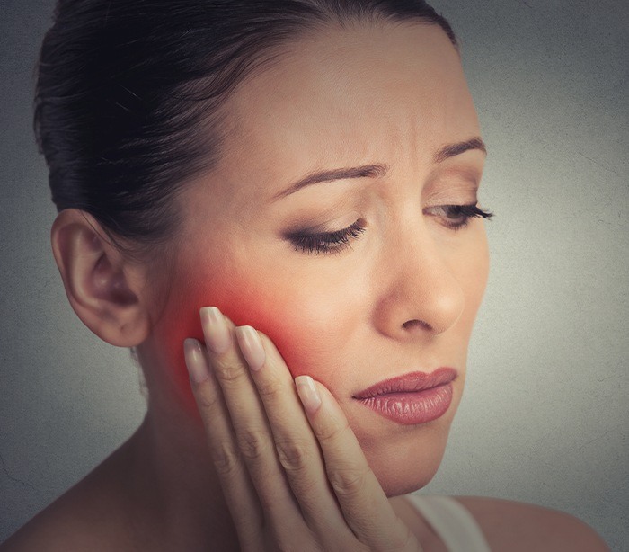 Woman in need of tooth extraction holding jaw