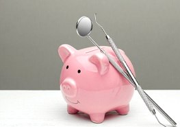 dental instruments resting on a pink piggy bank