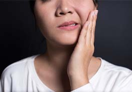 woman holding jaw after getting dental implants in Sunnyvale