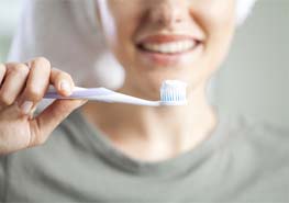 woman brushing teeth after getting dental implants in Sunnyvale